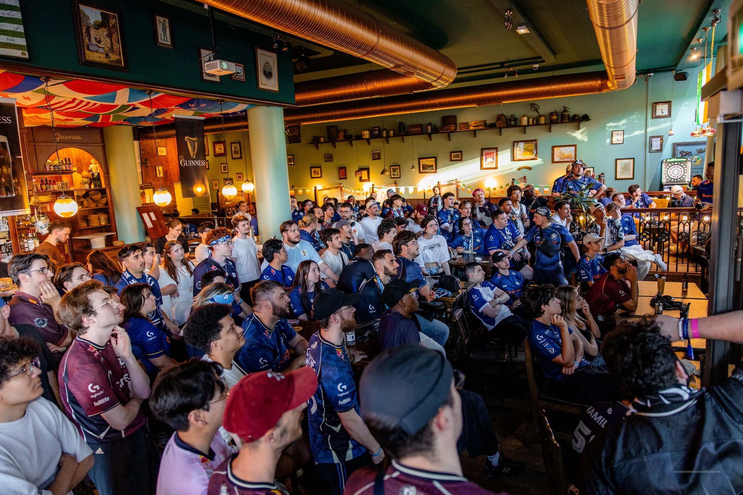 Supporters en maillot Karmine Corp autour d'une table dans un bar